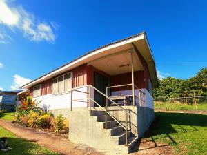 ‘OhonuaEua Accommodation的红色和白色的房子,设有门廊和楼梯