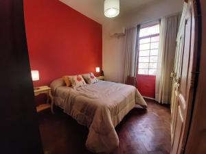 里奥夸尔托CasaOma的一间卧室设有一张床和红色的墙壁