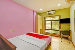 KondottiOYO Flagship Karipur Residency的一间卧室设有粉红色和黄色的墙壁和一张床