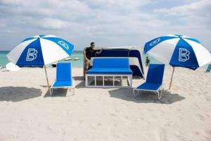 迈阿密海滩4 RM on Beach SoBeSuites by AmericanVacationLiving的坐在海滩帐篷前的人