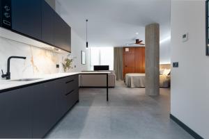 瓦伦西亚Calatrava by Alma Suites的一间带黑色橱柜的厨房和一间卧室