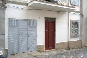 PietraperziaAppartamento ammobiliato的一座建筑,设有两个车库门和红色的门