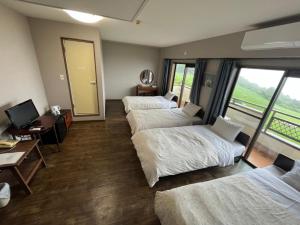 对马市Tsushima Dae-A Hotel的客房设有四张床、一张书桌和一台电视。