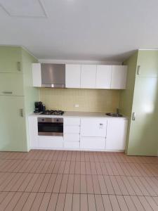 格莱内尔格Colley 11-11 Sub-Penthouse Luxurious Glenelg的厨房配有白色橱柜和瓷砖地板。