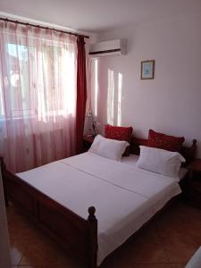 南埃福列casa andrei m的一间卧室配有一张大床,配有白色床单和红色枕头