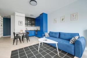 华沙Apartamenty Stadion Narodowy的客厅配有蓝色的沙发和桌子
