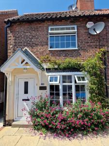 鲍特里Cosy Cottage 1 - Central Bawtry - 2 Bedroom - High End Furnishings的砖屋,有白色的门和一些花