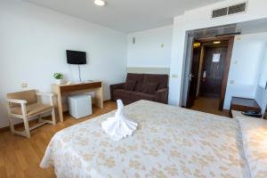 马塔拉斯卡尼亚斯弗拉梅罗酒店的一间卧室配有一张床、一张沙发和一台电视