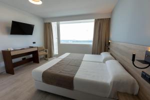 马塔拉斯卡尼亚斯弗拉梅罗酒店的酒店客房设有一张大床和一张书桌。