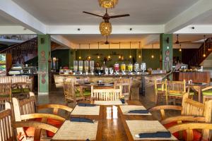 南威Nungwi Beach Resort by Turaco的一间带木桌椅的餐厅和一间酒吧