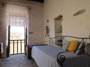 阿诺锡罗斯Philoxeno Traditional house - Ano Syros的一间卧室设有一张床,窗户的墙壁上有一个十字架