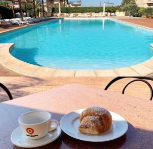 拉扎罗Villaggio Magna Grecia的在游泳池畔的桌子上喝杯咖啡和糕点