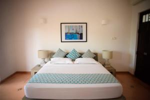 乌纳瓦图纳翠鸟酒店的卧室配有带蓝色枕头的大型白色床