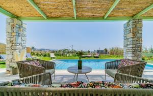 米科利维亚Plioni Villas & Suites的一个带桌椅的庭院和一个游泳池