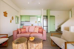 米科利维亚Plioni Villas & Suites的客厅配有粉红色的沙发和桌子