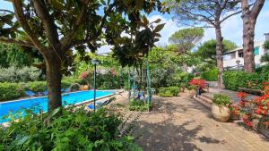 阿纳卡普里Villa Matisse - Damecuta Park的花园设有游泳池,种有树木和鲜花