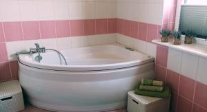 Rychtyńska Cisza的浴室设有浴缸,铺有粉色和白色瓷砖。