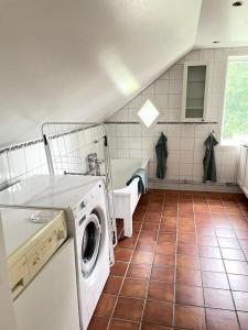 瓦伦蒂纳Charmig villa norr om Stockholm的铺有瓷砖地板,设有带洗衣机和烘干机的浴室。