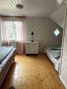 瓦伦蒂纳Charmig villa norr om Stockholm的一间卧室设有两张床、一个梳妆台和窗户。