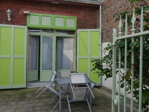梅尔·莱斯·拜恩斯La Maison Verte 71 m²的一个带绿门和桌椅的庭院