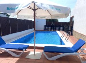 科尼尔-德拉弗龙特拉Casa independiente con piscina - Villa Pintor的游泳池旁的遮阳伞和椅子