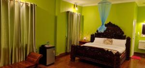 磅湛Toek Chha Temple Resort的一间卧室设有绿色的墙壁、一张床和椅子