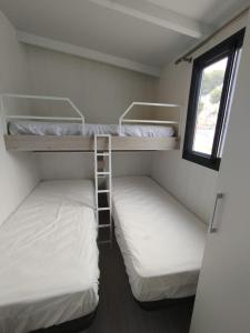 阿桂拉斯Bungalow Duemo Camperpark的小型客房设有两张双层床和窗户。