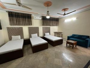 伊斯兰堡Decent Lodge Guest House F-11的一间设有两张床和蓝色沙发的房间