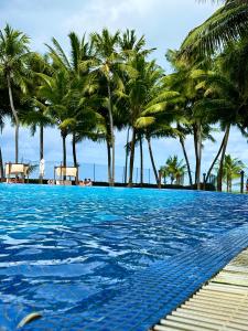 马塞约Jatiuca Suítes Resort FLAT的海滩上种有棕榈树的游泳池
