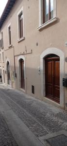 拉奎拉141 VIA ROMA的街道边的建筑,带有棕色门