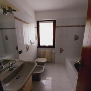 MassimenoAPPARTAMENTO OLGA的一间带水槽和卫生间的浴室以及窗户。