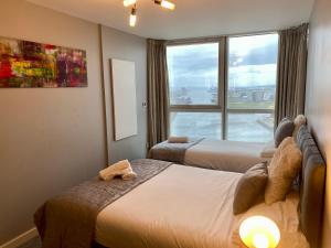 贝尔法斯特Titanic and Sea View Belfast 2 bedroom Apartment City Centre的酒店客房设有两张床和窗户。