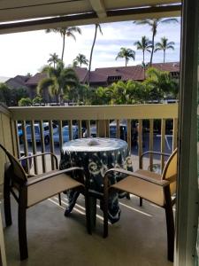 基黑Maui Diver's Dream at Kihei Bay Surf的棕榈树阳台的桌椅
