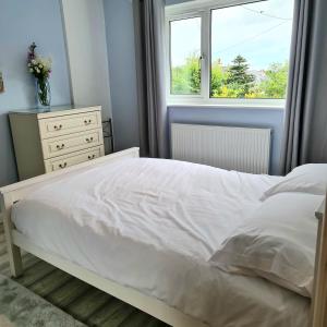 本莱赫Benllech Beach的卧室配有白色的床和窗户。
