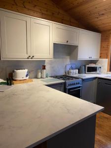 罗厄德南Cozy Cabin with Stunning Loch Lomond Views的厨房配有白色橱柜和台面