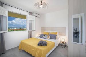 勒拉芒坦Navira - Appartement le Pavillon的一间卧室配有一张带黄色毯子和窗户的床