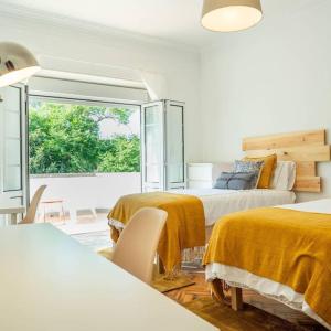 奥埃拉斯Lisbon Blue House的白色的客房设有两张床和窗户。