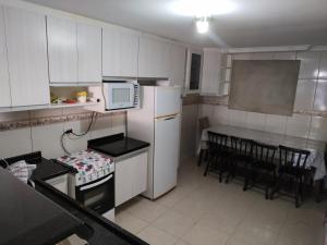 圣若泽杜斯皮尼艾斯Casa Térrea Oliveira inteira的厨房配有白色冰箱和桌椅