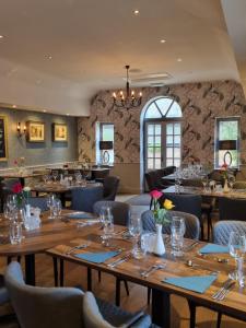 Stoke Albany白马旅馆及餐厅的餐厅设有木桌、椅子和吊灯。