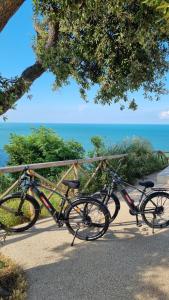 洛雷托B&B Ceresà - Country House的两辆自行车停在靠近海洋的围栏旁边