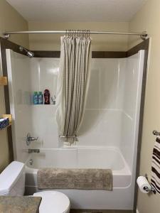 舍伍德帕克Dragonfly Inn Loft & Walkout Suites的浴室配有白色浴缸和卫生间。