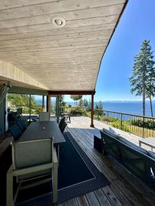 半月湾Barooga: Stunning View Home in Halfmoon Bay, Canada的一个带桌椅的甲板和大海