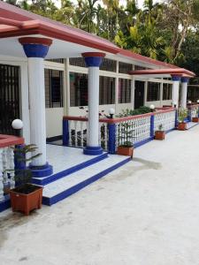 巴纳内拉斯Sunapur Mini Resort Sylhet的蓝白柱子和植物的建筑