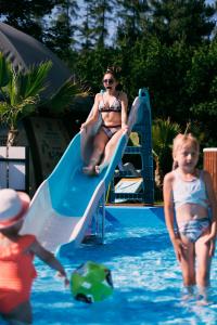 布伦纳库塔尔兹Spa加康体酒店的游泳池滑梯上的一名妇女和两名儿童