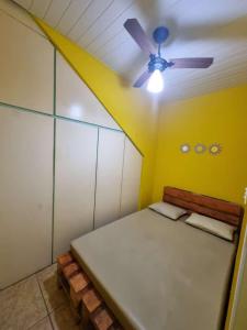 曼加拉蒂巴Cantinho Feliz de Muriqui / Casa amarela的客房设有一张床和一个吊扇。
