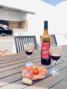 亚伊萨Casa Gercko 2的木桌旁的一瓶葡萄酒和两杯酒