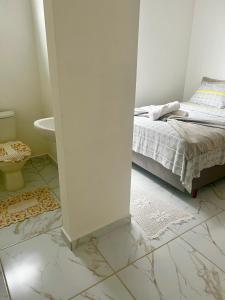 南圣弗朗西斯科Suítes Recanto Monte trigo的一间白色卧室,配有床和一间浴室