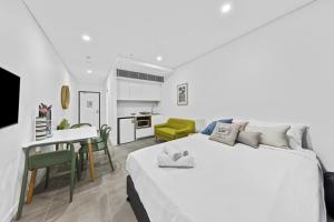 悉尼Arthur's Hotel Bondi Junction的一间白色卧室,配有一张大床和一个厨房