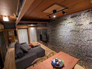 尾道市SIDOU 　INN的带沙发和石墙的客厅
