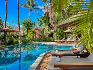 暹粒Natural Relax Villa的一个带椅子和棕榈树的度假村游泳池